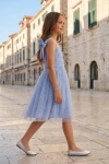Abito Rina azzurro fiordaliso – bambina in una via del centro storico, figura intera di profilo