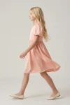 Abito Sia rosa per bambina – profilo con la gonna svasata sopra il ginocchio in movimento