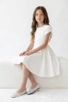 Abito Rumi bianco – bambina seduta su una panchina bianca, vista frontale