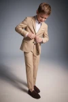 Completo Liam beige per bambino – giacca e pantaloni, bambino che abbottona la giacca, vista frontale