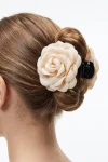 Pinza per capelli con rosa in tessuto beige appuntata su uno chignon – vista da dietro