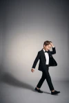 Completo Sam nero con papillon – bambino in movimento su fondo grigio, giacca aperta, figura intera